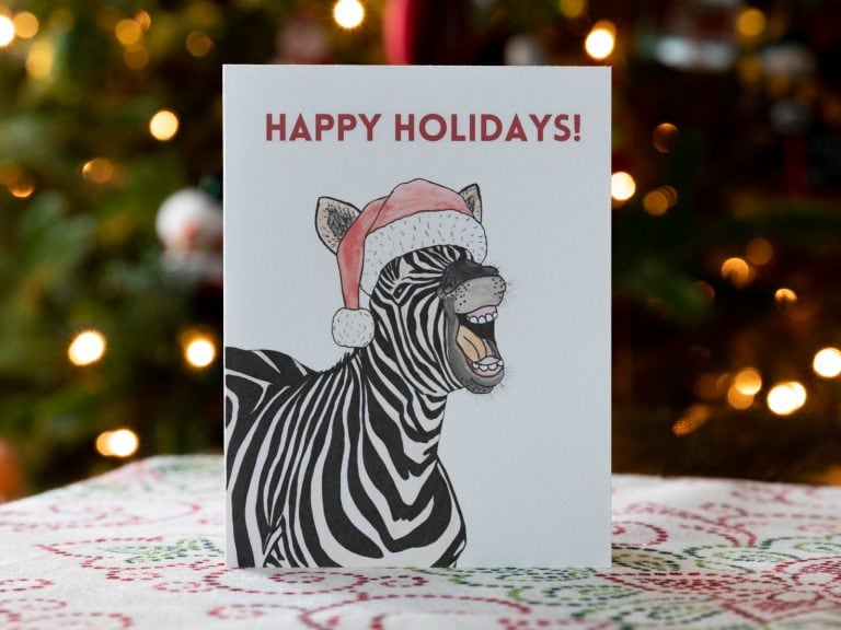 Holiday card featuring a zebra in a stanta hat. The card reads Happy Holidays!